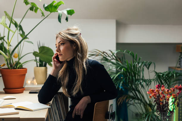 istock Young Caucasian Female Professional Working from Home- Sitting in her Office Area while Using Smartphone (Horizontal) 1312755527