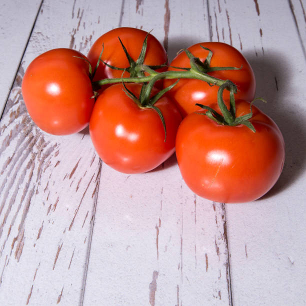 istock Tomatoes on a branch close-up on a white table, copy space, template 1312757453