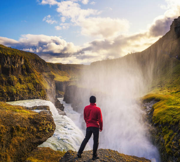 joven excursionista de pie en el borde de la cascada gullfoss en islandia - gullfoss falls fotografías e imágenes de stock