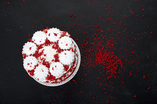Delicious homemade red velvet cake with meringue and mascarpone cream on black background. Top view, copy space