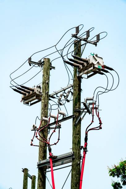 Electricity power supply Electricity mains supply close up, overhead power lines against a blue sky, UK utility pole with power lines close up stock pictures, royalty-free photos & images
