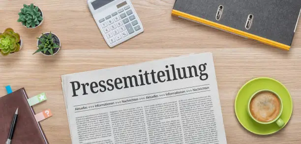 A newspaper on a desk with the headline Press Release in german - Pressemitteilung