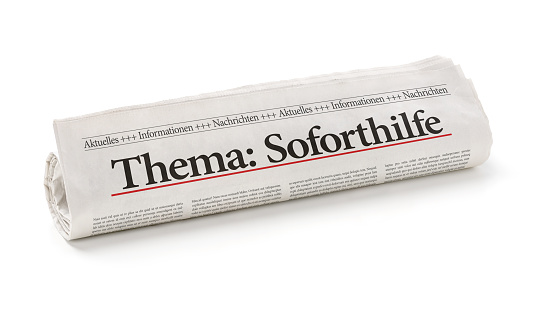 Rolled newspaper with the headline Emergency Aid in german - Soforthilfe
