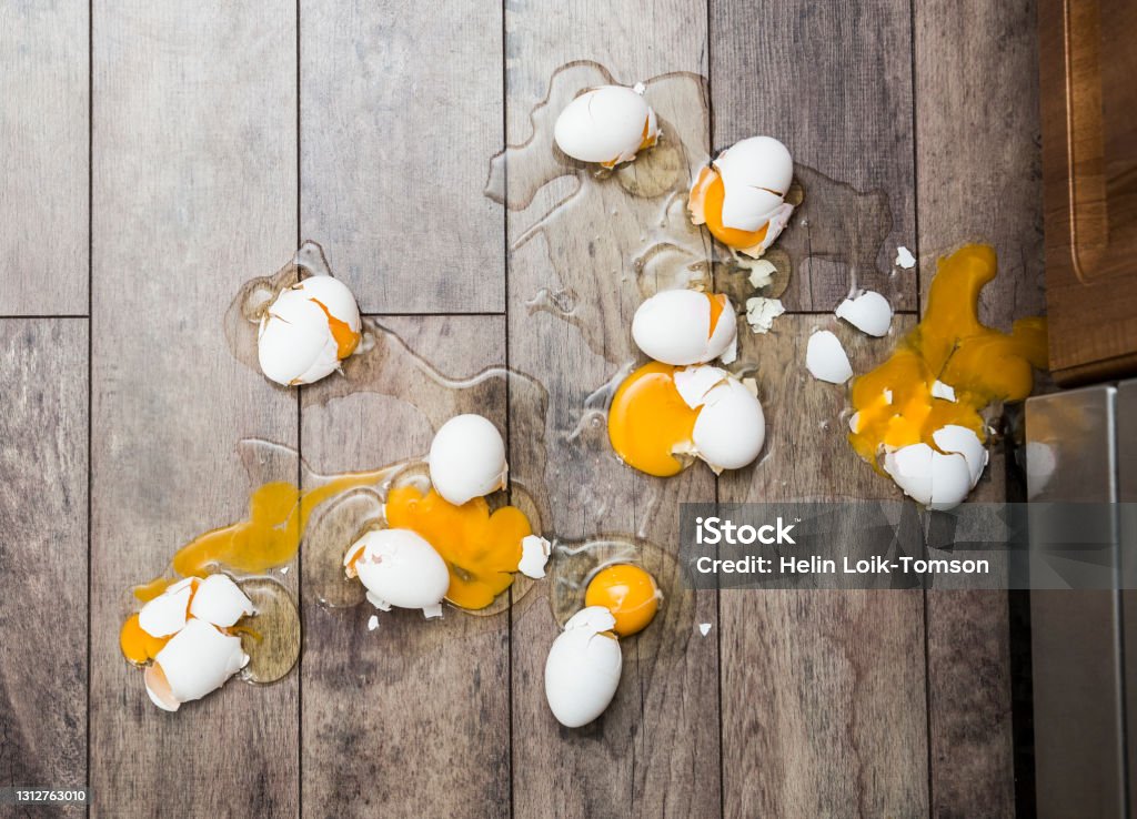 Lot of broken eggs on brown home floor. Misfortune concept. Animal Egg Stock Photo