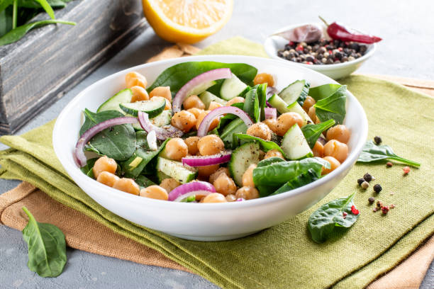 istock Chickpea salad with cucumber, spinach, parsley, onions and lemon in a plate on a served table. Tasty and healthy vegetarian food, oriental and Mediterranean cuisine. 1312763702