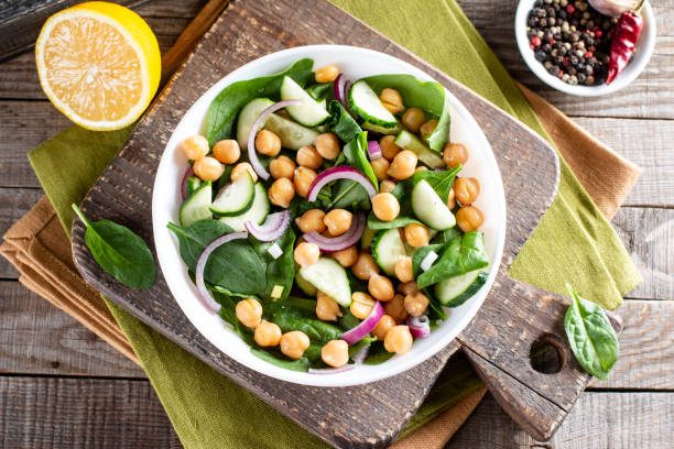 istock Spinach, cucumber, chickpeas, onions and lemon salad on a table. Top view 1312763759