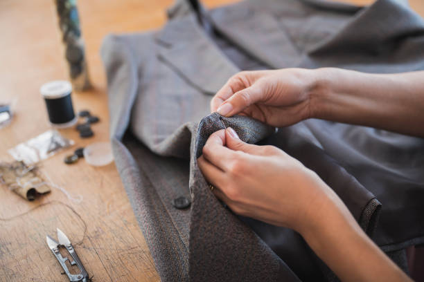 Female tailor finishing off hand stitched button on jacket