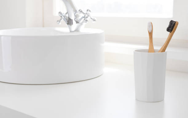 Clean bathroom counter with two different bamboo toothbrushes in holder Clean bathroom counter with two different bamboo toothbrushes in holder toothbrush stock pictures, royalty-free photos & images