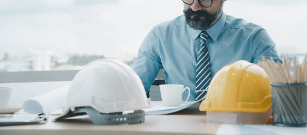 istock Engineer or architect working in office with safety helmet on desk  with copy space 1312767649