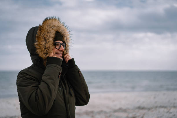 istock Man With Hooded Jacket Standing At Beach Against Sky During Winter 1312767847