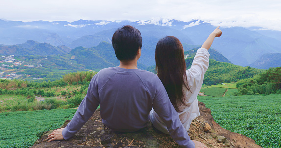 asian couple sit in tea plantation and enjoy the view