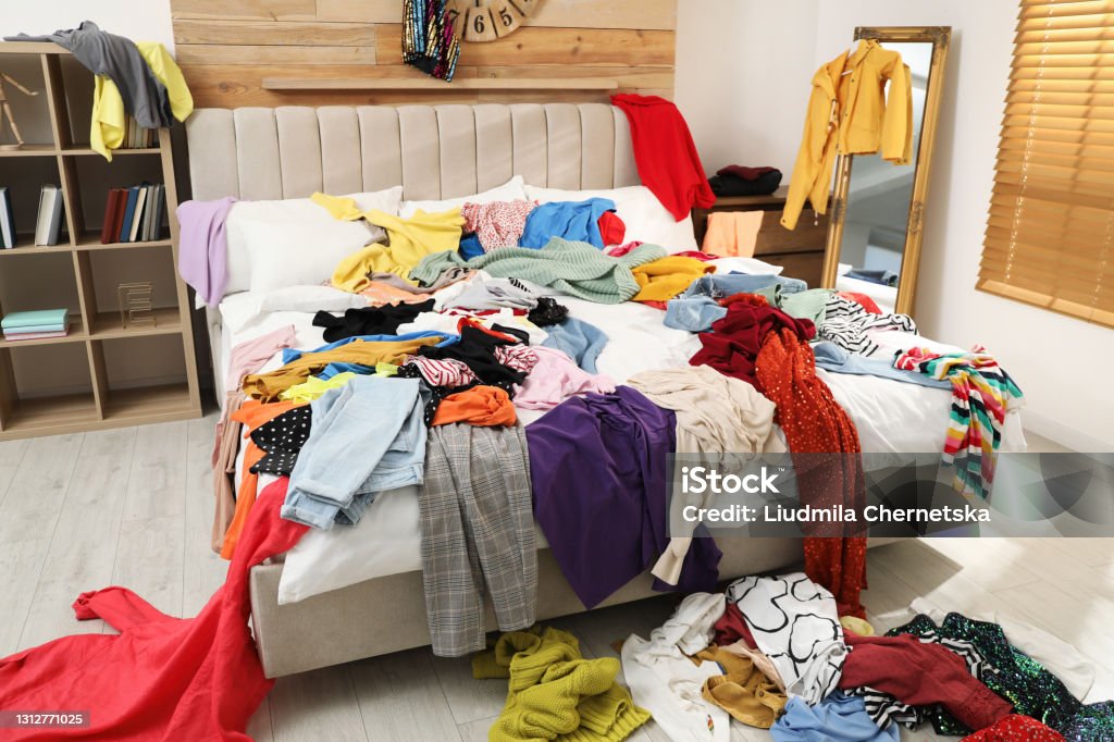 Pile of clothes on bed in messy room. Fast fashion concept Messy Stock Photo