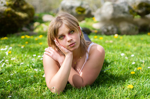 Portrait of blonde woman lying on grass in park