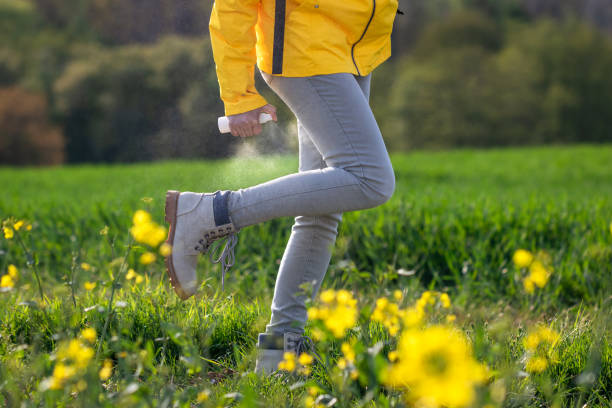 Woman spraying insect repellant against tick and bug bite Hiker spray insect repellent against tick and mosquito bite on her legs and boots bug bite stock pictures, royalty-free photos & images