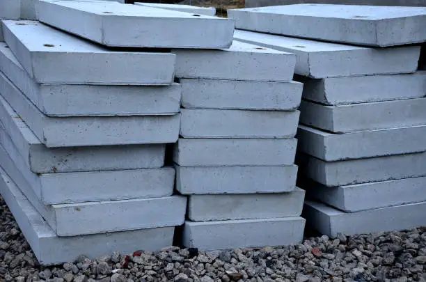 warehouse of concreting panels in the concrete plant. production of ceiling lintels for the construction of houses, flat bridges and roads. gray heavy objects moved by a crane