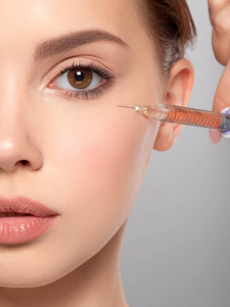 mujer recibiendo inyección cosmética de botox en la cara, primer plano.  inyección cerca del ojo.  mujer en salón de belleza, clínica de cirugía plástica. concepto de procedimientos de cosmetología. terapia de tratamiento de belleza. - attractive female human collagen syringe injecting fotografías e imágenes de stock