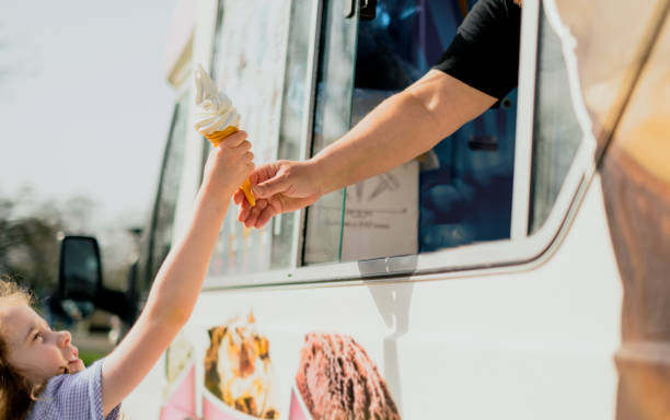 une petite fille heureuse obtenant la crème glacée - camionnette de vendeur de glaces photos et images de collection