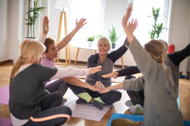 istock Senior people sitting in circle and stacking hands together after successful yoga class in yoga studio 1312788029