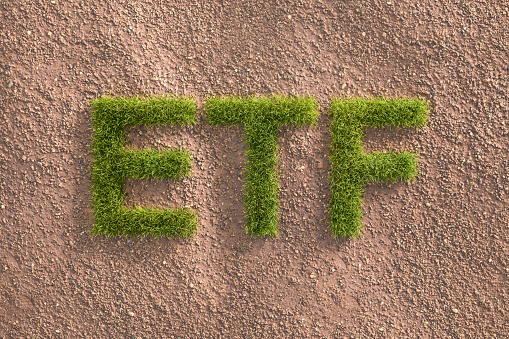Green grass letters ETF in an arid landscape. Concept for  Exchange traded funds investing by ESG standards (environment social governance).