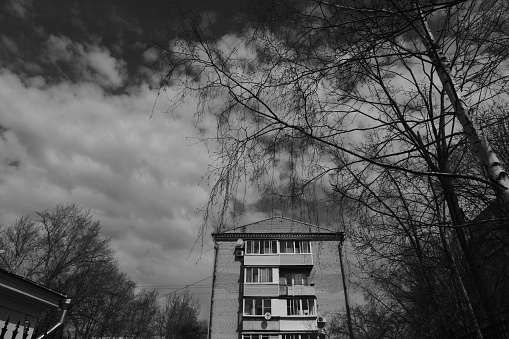 Moscow region, Russia - April 16, 2021: Top section of apartment house in the frame of tree branches