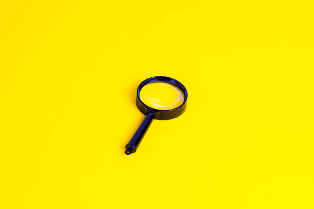 istock Black magnifying glass on light yellow background 1312790315