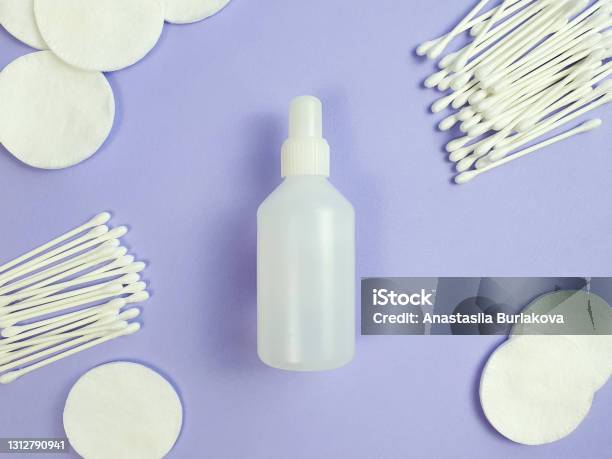 Unbranded White Plastic Bottle Of Disinfectant Cotton Pads And Sticks On Purple Background Natural Organic Spa Cosmetics And Liquid Antimicrobial Concept Flatlay Style Top View Stock Photo - Download Image Now