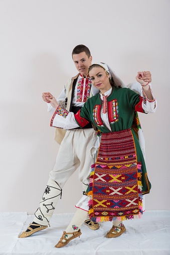 Beautiful young people in traditional Bulgarian costumes pose in the photo studio for photos.