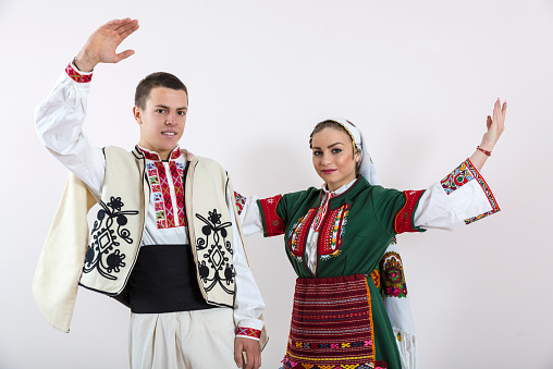 Beautiful young people in traditional Bulgarian costumes pose in the photo studio for photos.