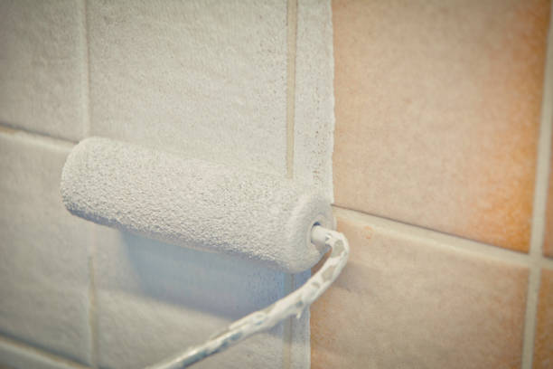 istock Painting old tiles in the kitchen or bathroom white with a small roller and two component paint. 1312792616
