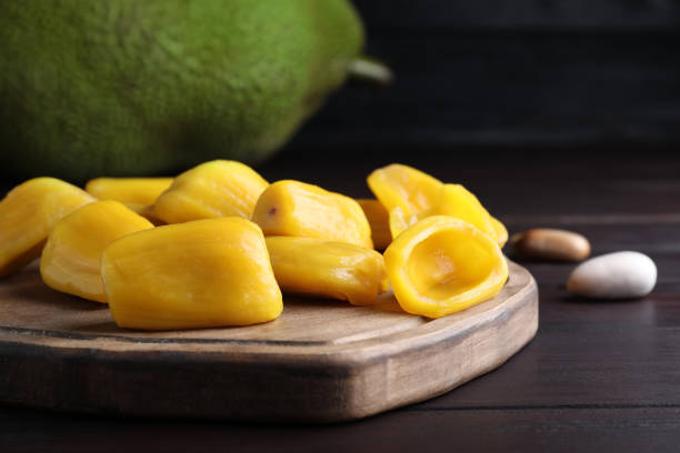 istock Fresh exotic jackfruit bulbs on black wooden table, closeup 1312794776