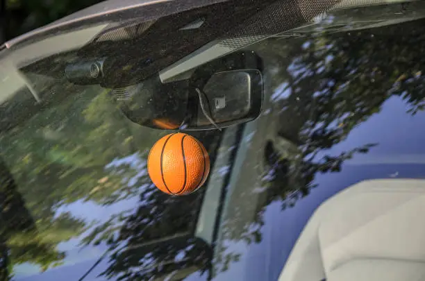 Photo of Keychain pendant in the form of a small basketball on the rearview mirror of a car.