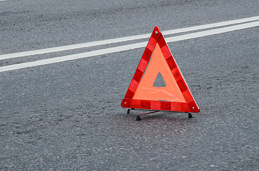 Red warning triangle on the carriageway with a double dividing strip. Traffic rules, traffic accidents, road safety.