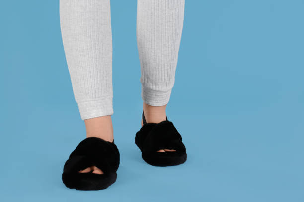 istock Woman in fluffy slippers on light blue background, closeup 1312795748