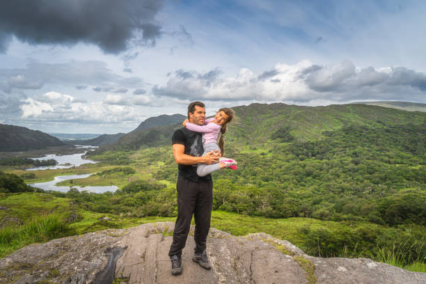 ojciec trzyma córkę na rękach i stoi na skale, ciesząc się pięknym ladies view - lakes of killarney zdjęcia i obrazy z banku zdjęć