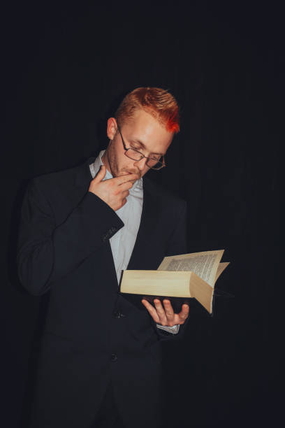 istock Young man or missionary reading the Bible isolated on black background 1312801344