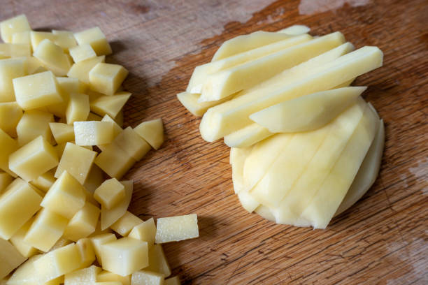 istock Cut fresh potatoes on wooden kitchen board 1312801635