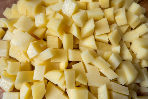 istock Cut fresh potatoes on wooden kitchen board 1312801893
