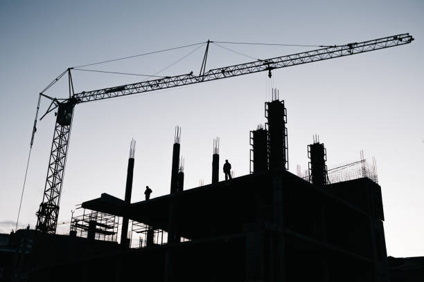 istock silhouette of builders on a high cement building that is being built with a Construction crane silhouette over them 1312802035