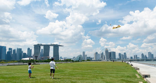 シンガポールの街のスカイラインを背景にマリーナ・バラージュで凧を飛ばす人々 - marina bay sands hotel architecture asia travel destinations ストックフォトと画像