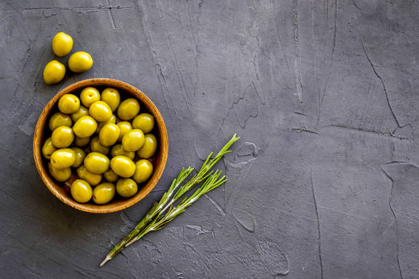 istock Wooden bowl with green olives. Overhead view, space for text 1312806496