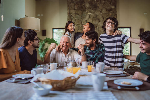 Happy grandfather surrounded with his family at breakfast Happy smiling grandfather surrounded with his big family at breakfast. multi generation family stock pictures, royalty-free photos & images