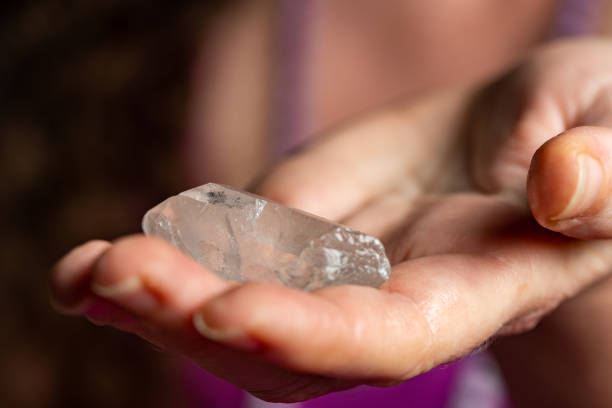 istock Raw Clear Quartz Crystal Held by Caucasian Woman's Hand 1312807577
