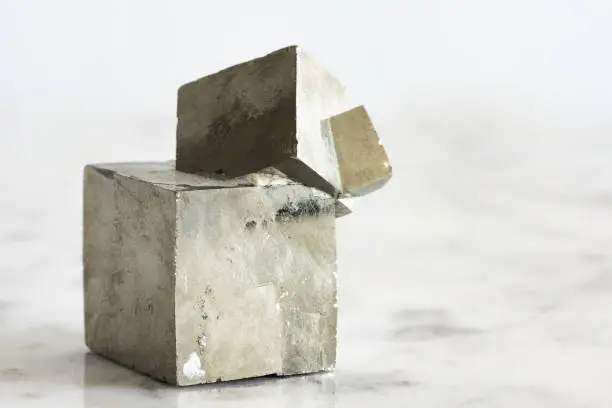 Photo of Metallic Fool's Gold Pyrite Cube on Marble Background