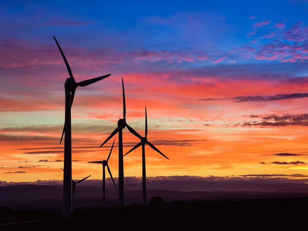 silhouettes of wind turbines at sunset.  Renewable energy concept. stock photo