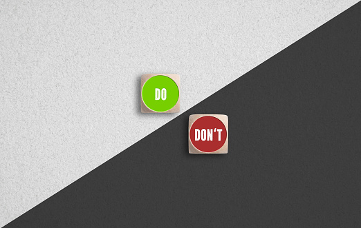 Do and Don't concept with red and green icons on dice arranged on either side of a diagonal white and black background in a concept of dilemma and leadership