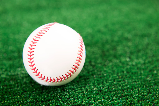 Collection of new and used baseballs on artificial turf.