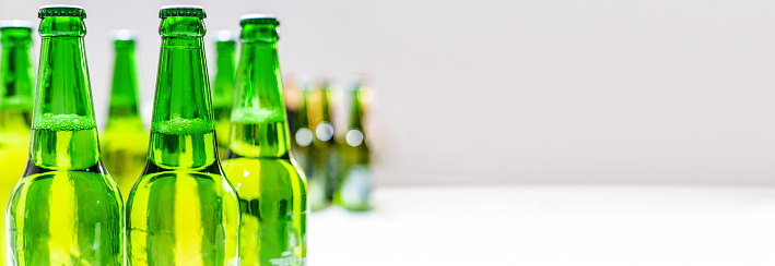 Group of a lot of green bottle beers with a blurry background. Bottle beers on the background. Horizontal picture.