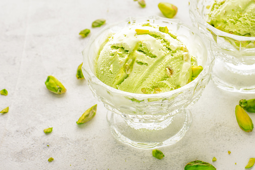 Close up pistachio ice cream in glass bowls and nuts.