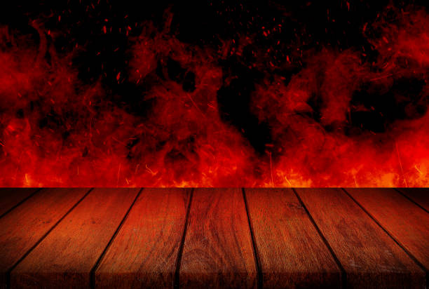 istock Empty wooden table top with orange fire or flame and sparkles in dark room. 1312827216