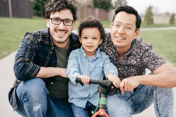 Photo of Happy family with two dads and toddler son